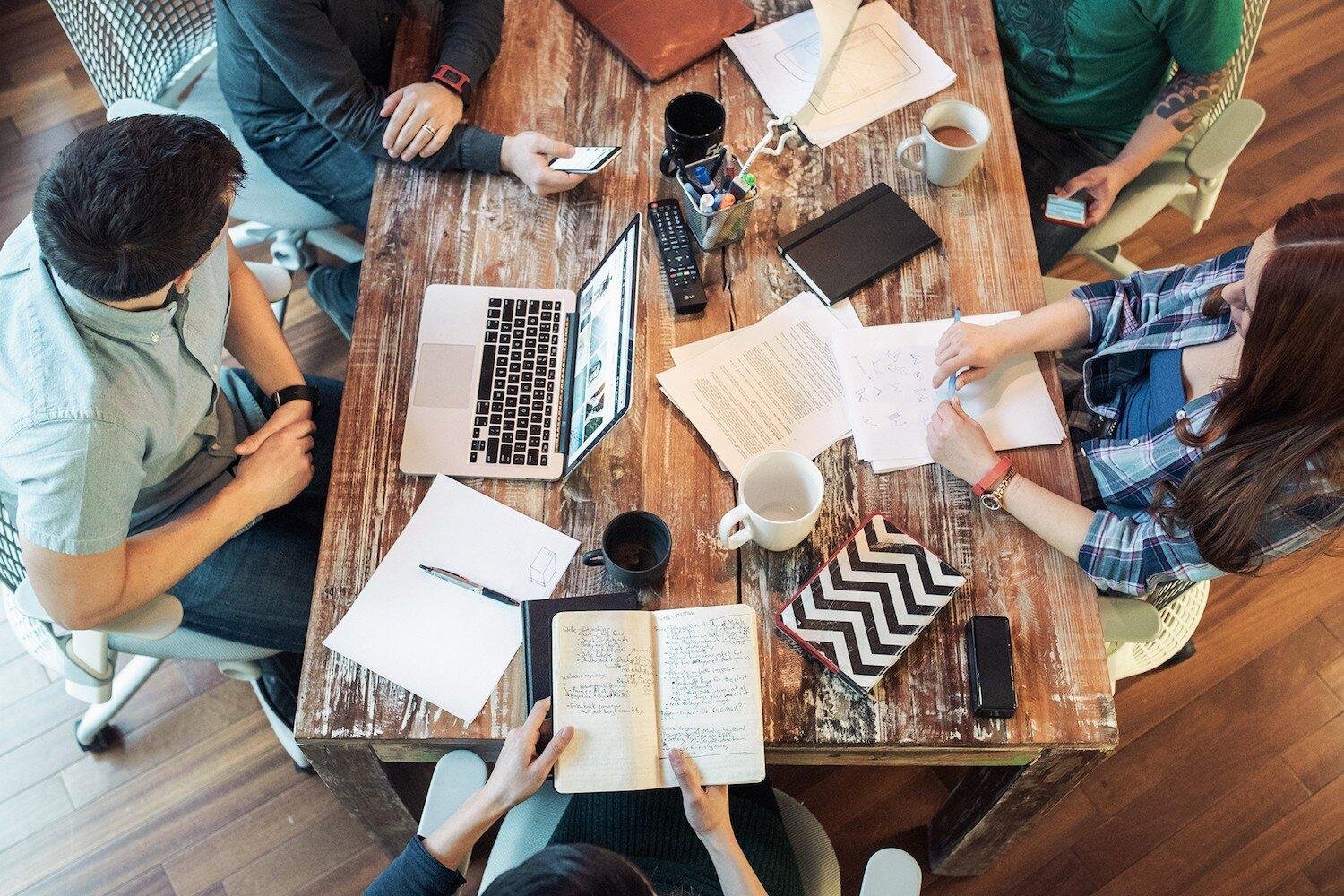 Table de travail avec carnets, documents et cafés lors d’un échange collectif